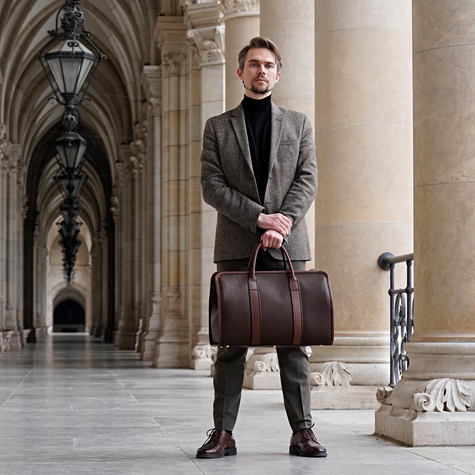 Mann hält Reisetasche aus Leder braun
